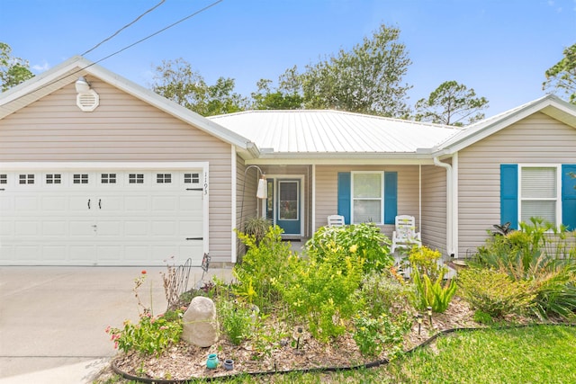 ranch-style home with a garage, metal roof, and driveway