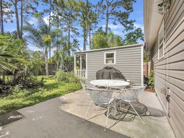 view of patio with fence, an outbuilding, and outdoor dining space