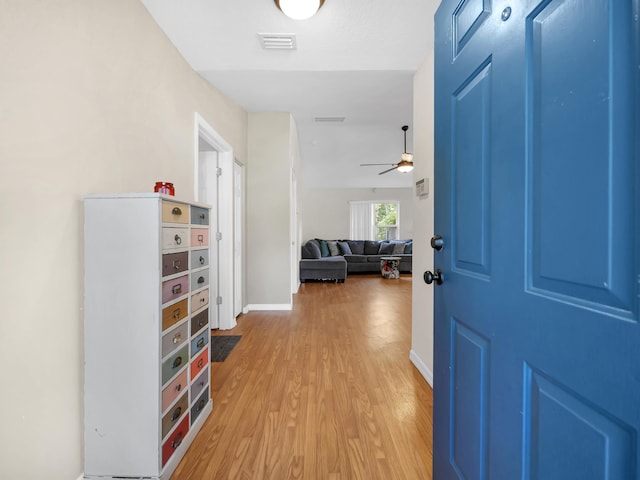 foyer with light wood-style flooring, ceiling fan, and baseboards