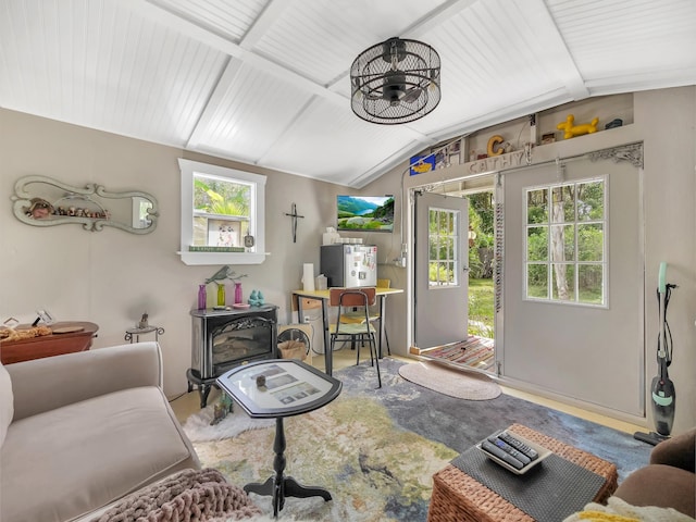 living room featuring vaulted ceiling, plenty of natural light, and a wood stove