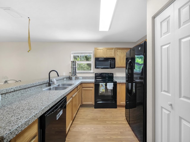 kitchen featuring black appliances, a sink, and light wood-type flooring