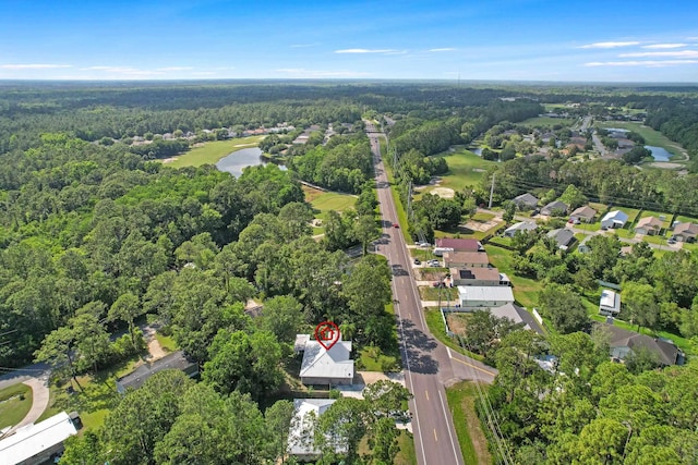 view of property location featuring a forest, a large body of water, and nearby suburban area