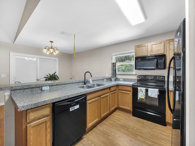 kitchen with black appliances, a sink, light wood-type flooring, a peninsula, and a chandelier