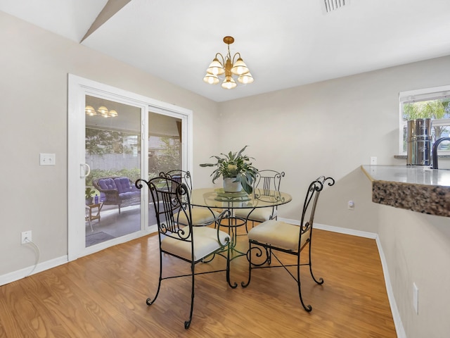 dining space featuring a chandelier, wood finished floors, and baseboards