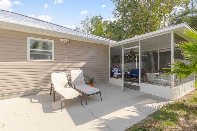 view of patio / terrace featuring a ceiling fan and a sunroom