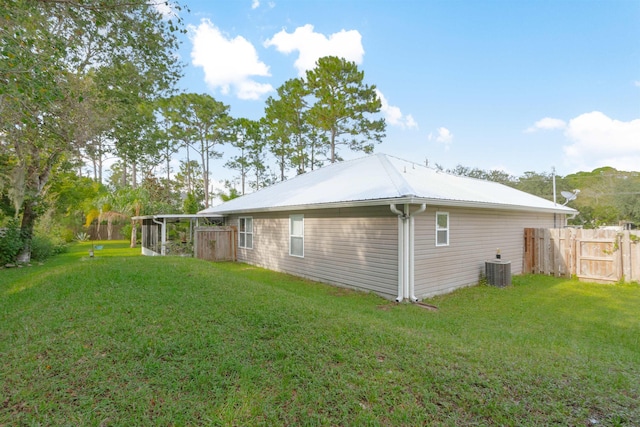rear view of property featuring central AC, metal roof, a gate, and a sunroom