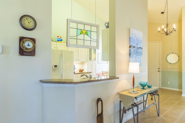 kitchen featuring a breakfast bar, decorative light fixtures, kitchen peninsula, white fridge with ice dispenser, and white cabinets