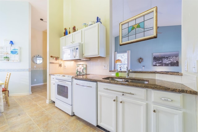 kitchen with white cabinetry, sink, backsplash, dark stone counters, and white appliances