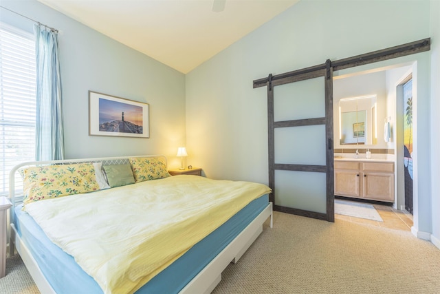 carpeted bedroom with ceiling fan, lofted ceiling, a barn door, and ensuite bathroom