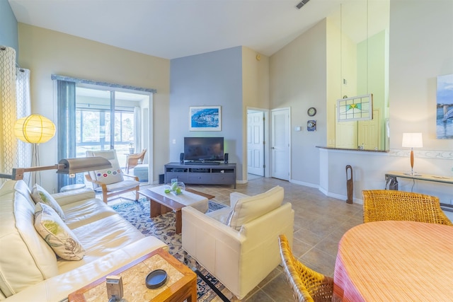 living room with a towering ceiling and tile patterned floors