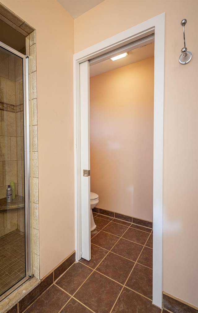 bathroom with toilet, an enclosed shower, and tile patterned flooring