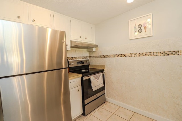 kitchen with light tile patterned flooring, stainless steel appliances, tile walls, and white cabinets