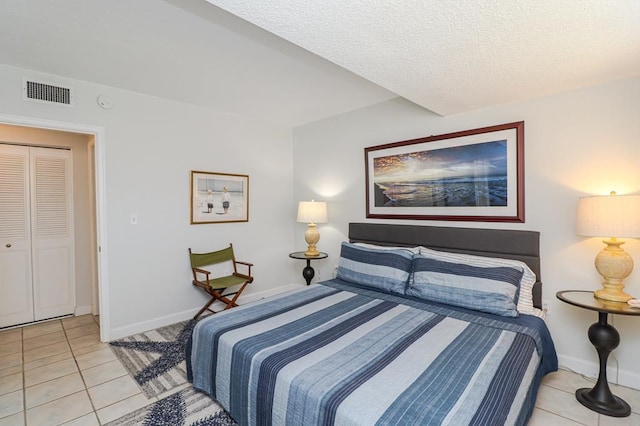 bedroom with light tile patterned floors, a closet, and a textured ceiling