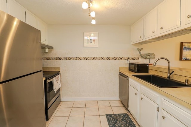 kitchen featuring light tile patterned floors, appliances with stainless steel finishes, sink, and white cabinetry