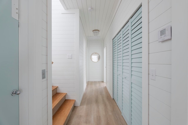 hall featuring wood walls, wooden ceiling, and light hardwood / wood-style flooring