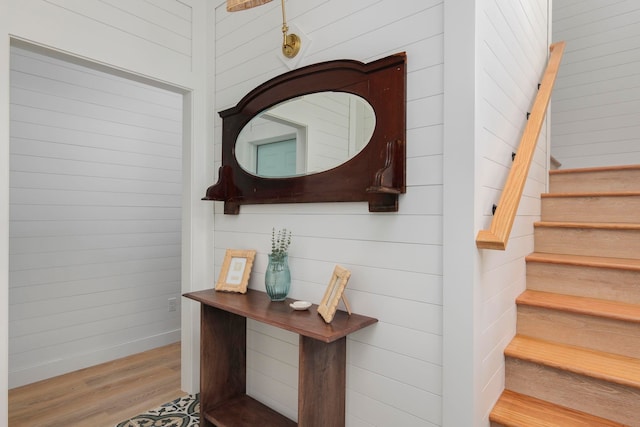 staircase with wood walls and wood-type flooring