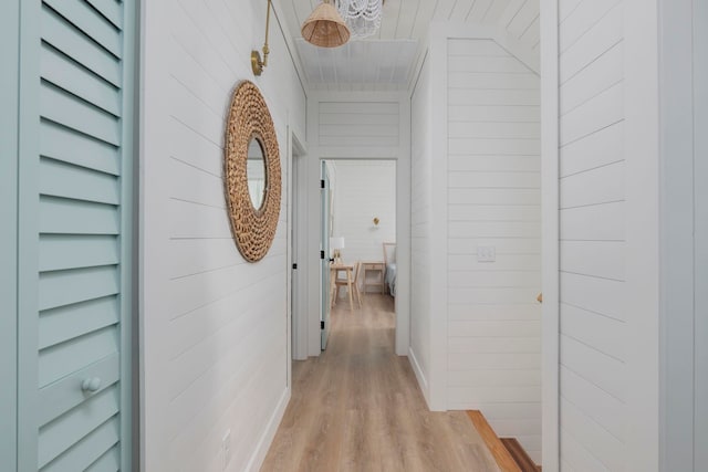 hall with light hardwood / wood-style floors and wooden walls