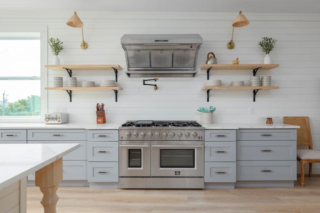 kitchen with hanging light fixtures, light hardwood / wood-style floors, range with two ovens, and plenty of natural light