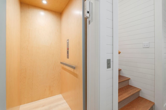 stairway featuring elevator and wooden walls