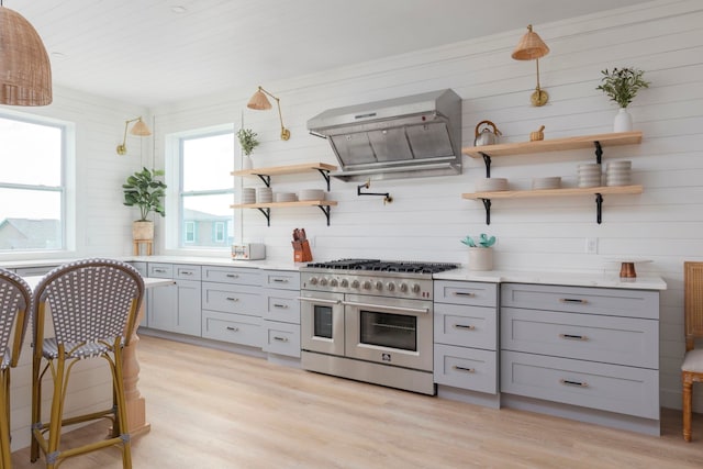 kitchen with gray cabinets, light hardwood / wood-style floors, double oven range, and extractor fan