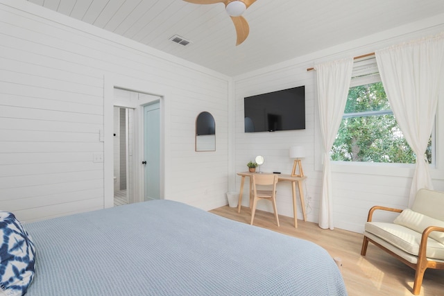 bedroom with wood walls, ceiling fan, and light hardwood / wood-style floors