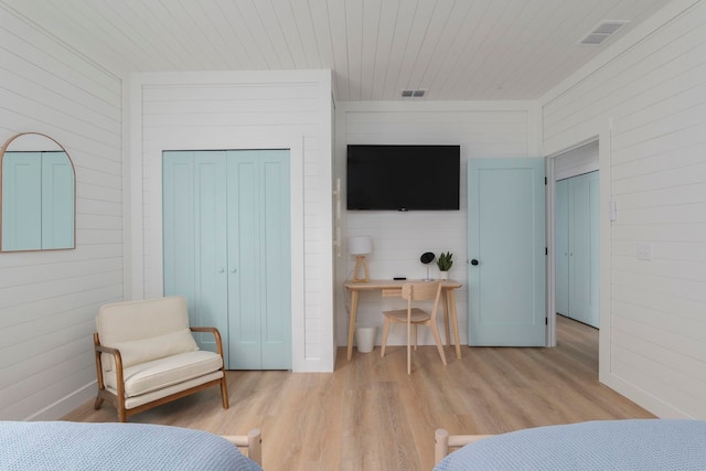 bedroom with wood walls, light wood-type flooring, and a closet