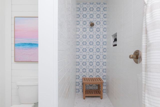 bathroom featuring toilet, walk in shower, and tile walls