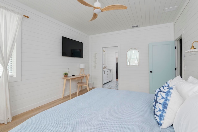 bedroom with ensuite bathroom, light hardwood / wood-style flooring, multiple windows, and ceiling fan