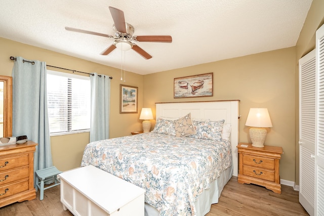 bedroom featuring ceiling fan, a closet, a textured ceiling, and light wood-type flooring