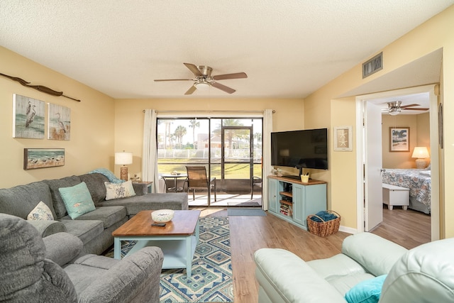 living room featuring a textured ceiling, light hardwood / wood-style flooring, and ceiling fan