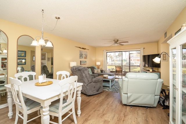 dining space featuring ceiling fan with notable chandelier, light hardwood / wood-style floors, and a textured ceiling