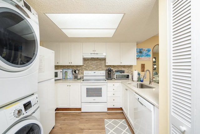 kitchen featuring backsplash, white appliances, sink, white cabinetry, and stacked washer / drying machine