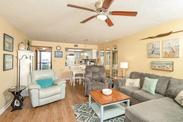 living room featuring a textured ceiling, light hardwood / wood-style flooring, and ceiling fan