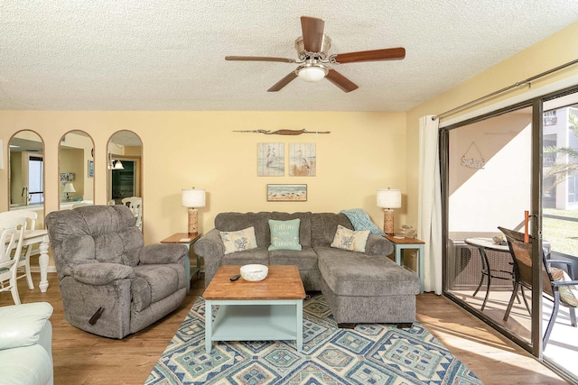 living room featuring ceiling fan, light hardwood / wood-style flooring, and a textured ceiling