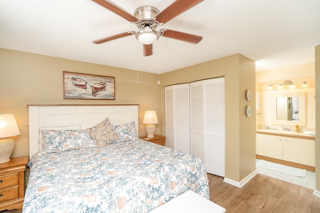 bedroom featuring connected bathroom, a closet, light hardwood / wood-style flooring, and ceiling fan