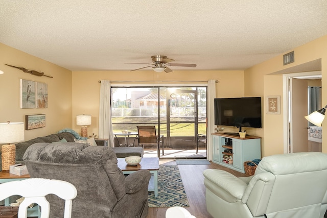 living room featuring ceiling fan, dark hardwood / wood-style flooring, and a textured ceiling