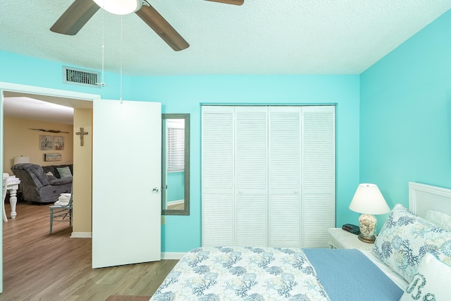 bedroom featuring ceiling fan, a closet, a textured ceiling, and light hardwood / wood-style flooring