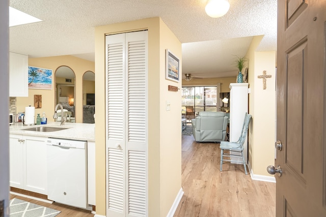 hall featuring light wood-type flooring, a textured ceiling, and sink