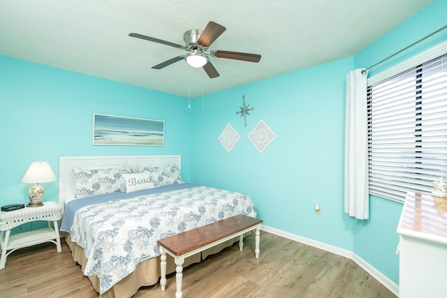 bedroom with ceiling fan, light hardwood / wood-style floors, and a textured ceiling