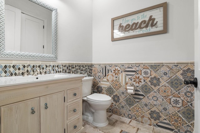 bathroom featuring toilet, tile walls, and vanity