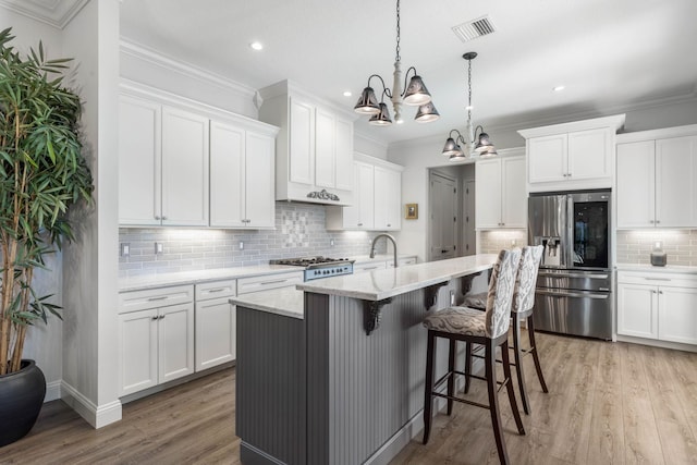 kitchen featuring hanging light fixtures, white cabinets, stainless steel fridge with ice dispenser, and a kitchen island with sink