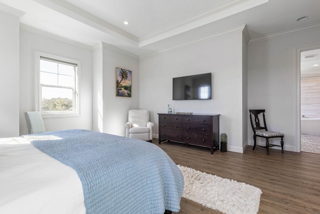 bedroom featuring connected bathroom, dark hardwood / wood-style floors, a raised ceiling, and ornamental molding