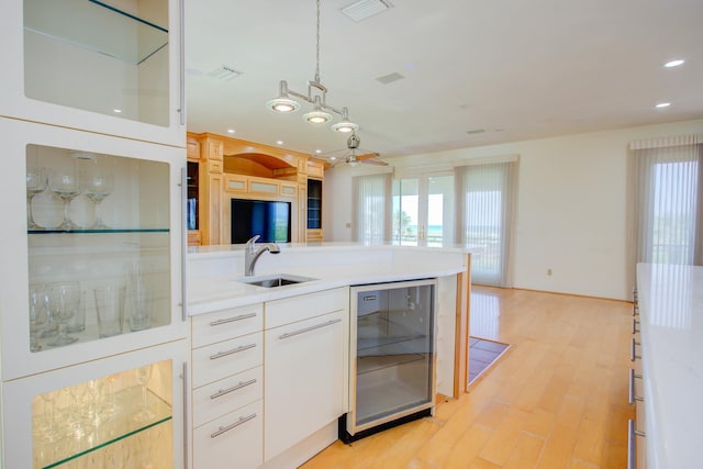 4 Oceanside Dr, Saint Augustine Beach, FL 32080 - kitchen with wine cooler, light countertops, a peninsula, light wood-style floors, and pendant lighting