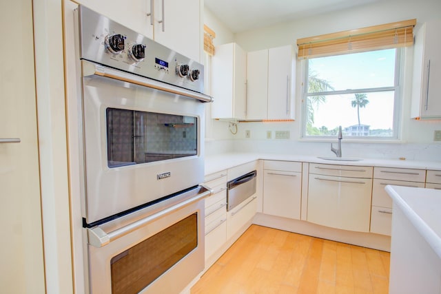 4 Oceanside Dr, Saint Augustine Beach, FL 32080 - kitchen featuring a warming drawer, light countertops, white cabinets, light wood-type flooring, and stainless steel double oven