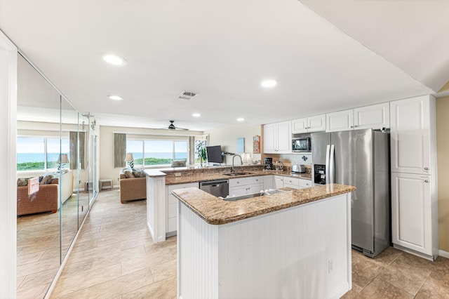 7780 S A1A Unit 101, Saint Augustine, FL 32080 - kitchen featuring appliances with stainless steel finishes, a peninsula, light stone countertops, open floor plan, and white cabinetry