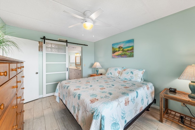7780 S A1A Unit 101, Saint Augustine, FL 32080 - bedroom with a barn door, wood finished floors, ceiling fan, and ensuite bath