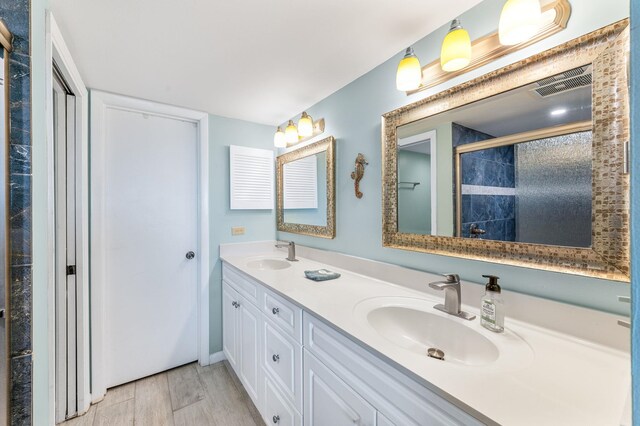 7780 S A1A Unit 101, Saint Augustine, FL 32080 - bathroom featuring double vanity, tiled shower, and wood finished floors