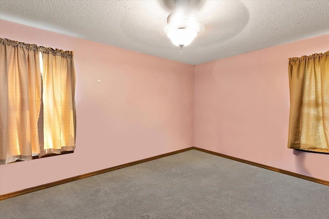 carpeted empty room featuring a textured ceiling