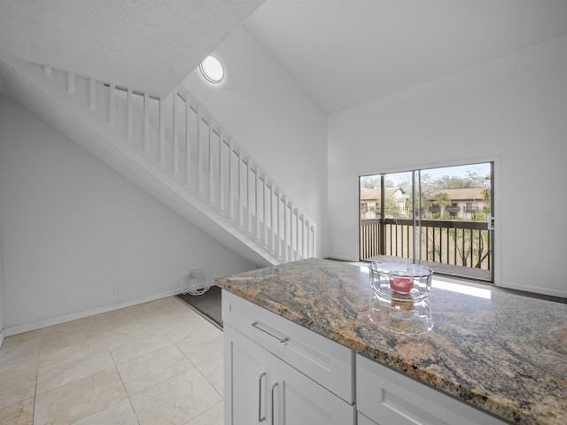 kitchen with baseboards, dark stone countertops, and white cabinets