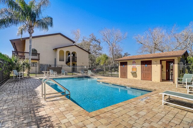 community pool featuring an outbuilding, a patio, and fence